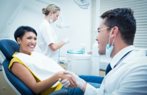 Dentist tending to patient in the chair while a dental tech prepares tools in the background.